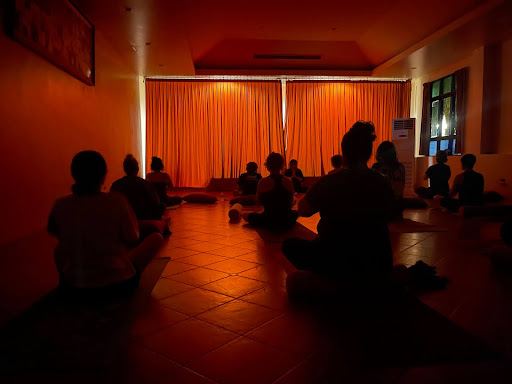 Evening yoga and meditation practice with students in a dimmed light room.
