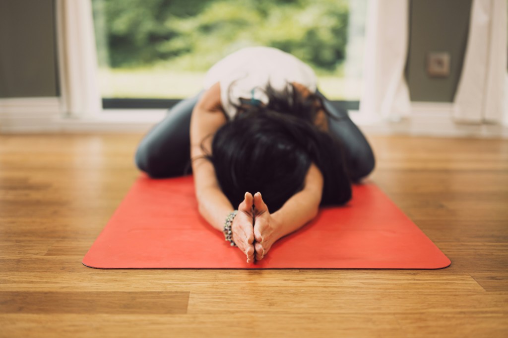 A woman in Extended Child's Pose on an orange mat.